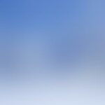 Blurry gradient background with blue and white tones.