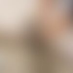 A blurred image with neutral tones and indistinct shapes.