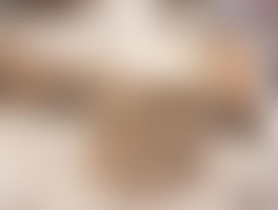 Blurry image of a person in a beige outfit in a warm-toned setting.