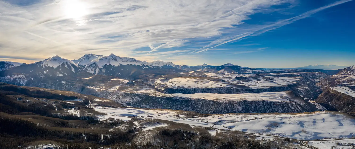 Snow-covered mountain range under a partly cloudy sky.